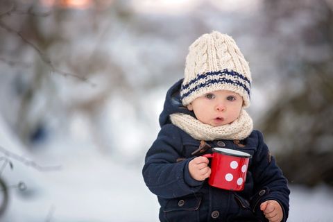 Baby trinkt im Winter draußen Tee aus einem Becher