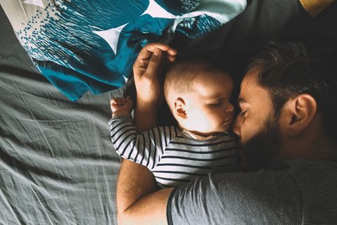 Baby und Vater schlafen im Bett
