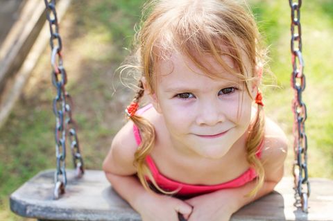 Einzelkinder-Erziehung: Kind auf Schaukel lächelt verschmitzt