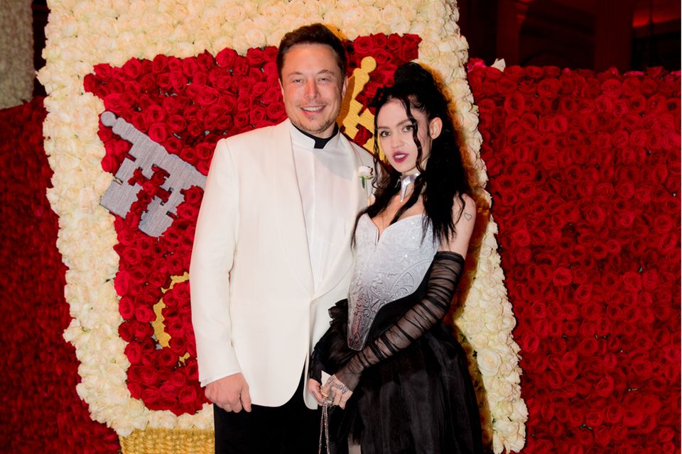 Elon Musk und Grimes posen vor einem Blumengemälde