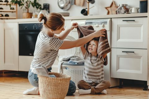 Gender Pay Gap: eine Mutter macht mit ihrem kleinen Sohn die Wäsche