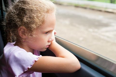 Gewalt gegen Kinder: ein kleines blondes Mädchen schaut traurig aus dem Fenster