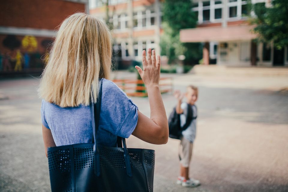 Mutter verabschiedet ihr Kind vor de Schule
