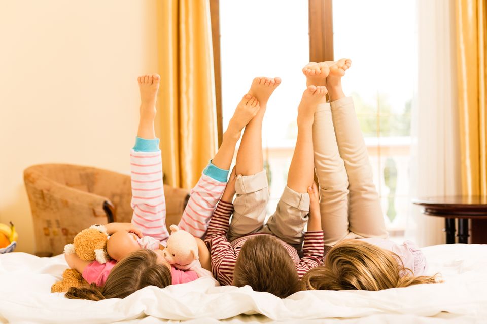 Kinder auf Hotelbett liegend mit Beinen in der Luft