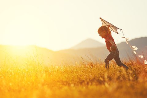 Mädchen lässt einen Drachen fliegen im Sonnenuntergang