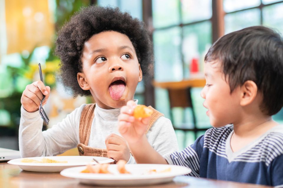 Zwei Kinder sitzen am Tisch und essen