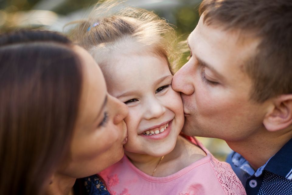 Eltern küssen ihre Tochter