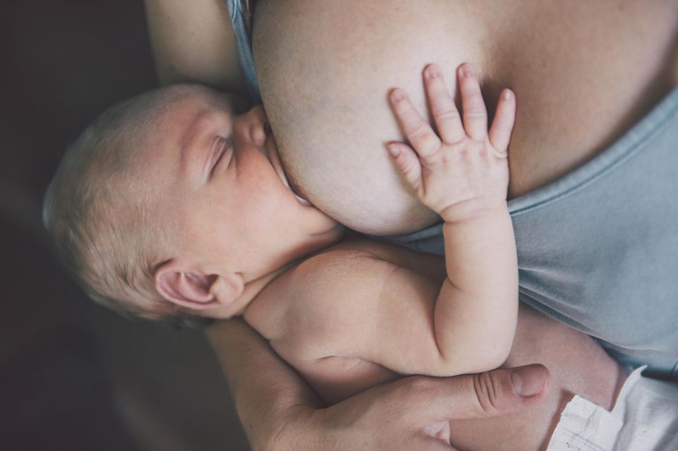 Eine Mutter stillt ihr Neugeborenes