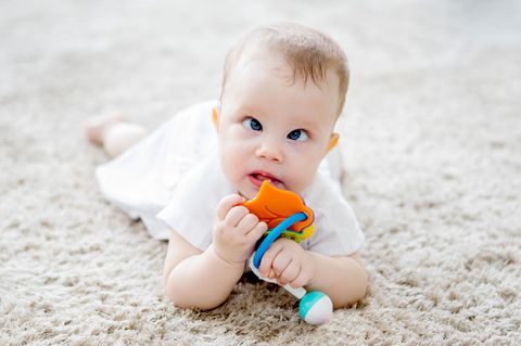 Schielen bei Babys: Schielendes Baby liegt auf dem Boden