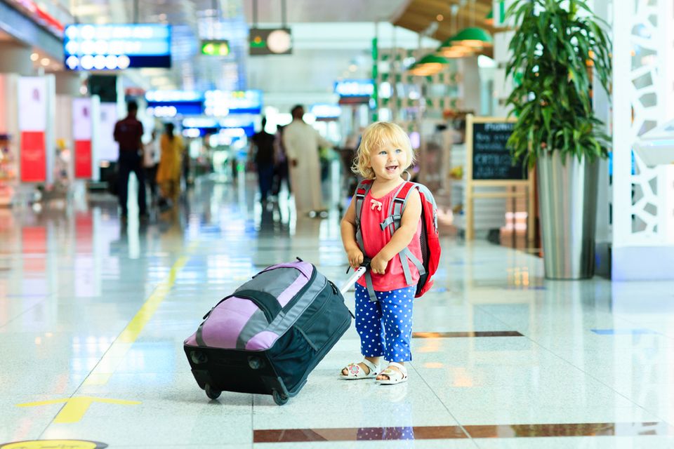 kleines Mädchen mit Koffer am Flughafen