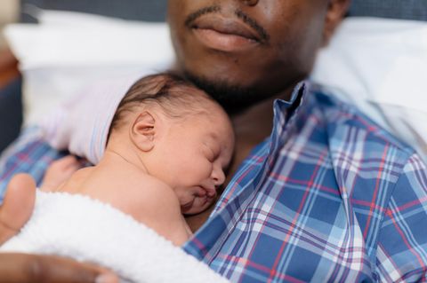 Vater kuschelt mit seinem Neugeborenen