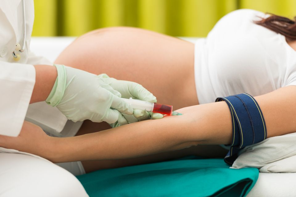 Schwangere liegt beim Arzt auf der Liege und kriegt Blut abgenommen