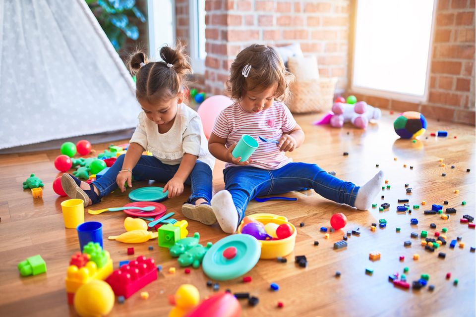 Zwei kleine Mädchen spielen im Kinderzimmer.