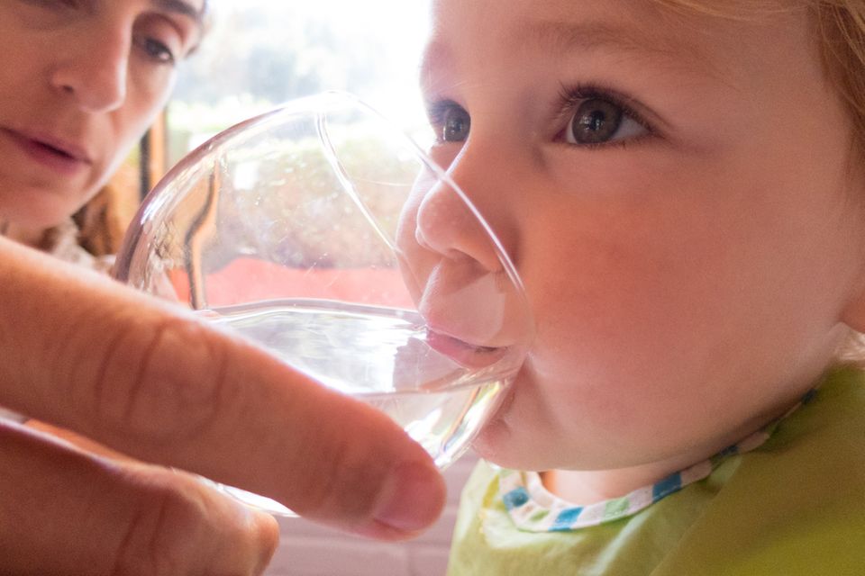 Baby trinkt Wasser aus Glas
