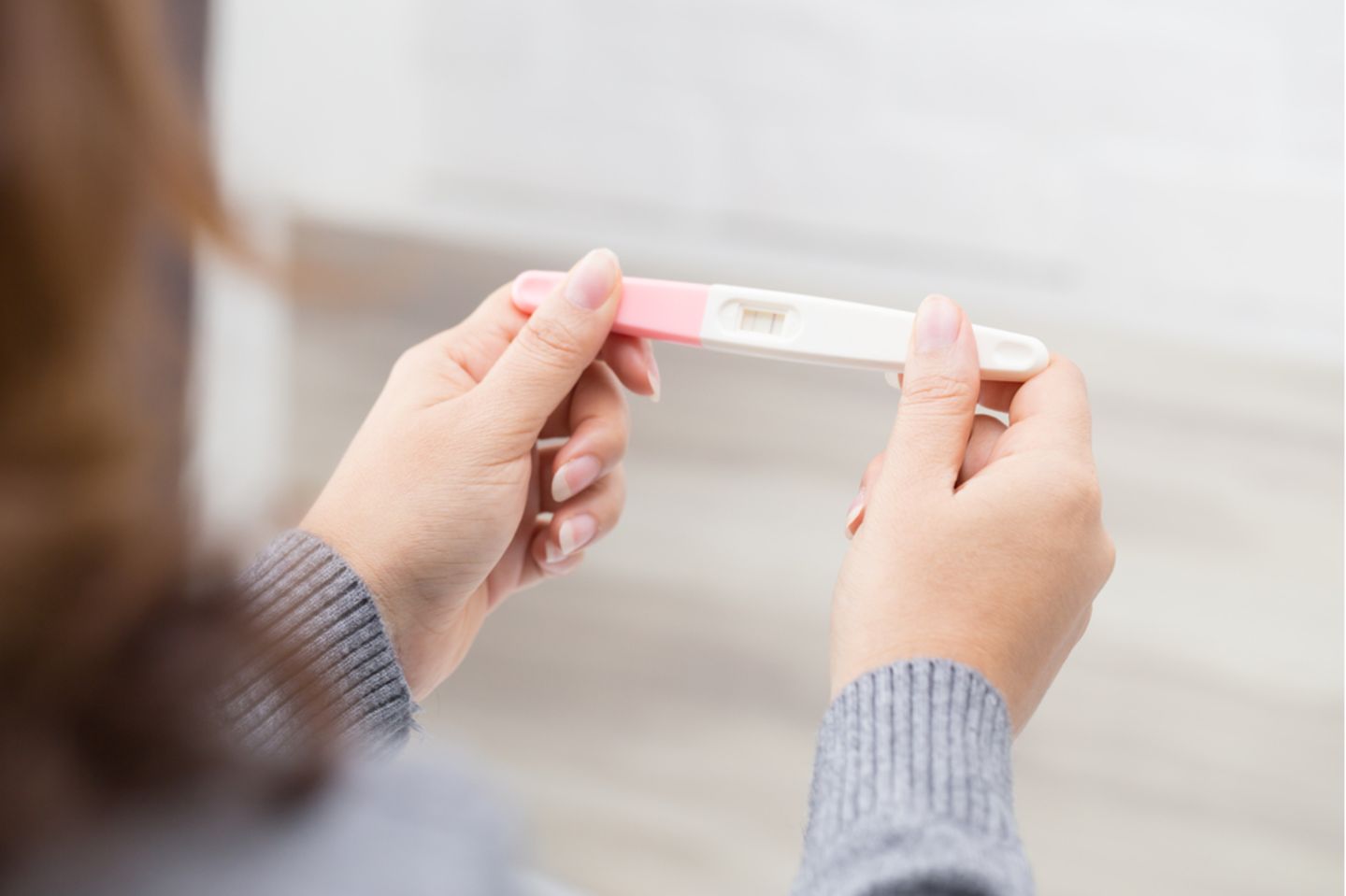 Bin ich schwanger? Eine Frau hält einen positiven Schwangerschaftstest in den Händen