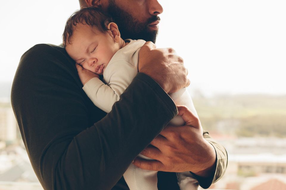 Ein frischgebackener Vater hält sein Neugeborenes auf dem Arm .