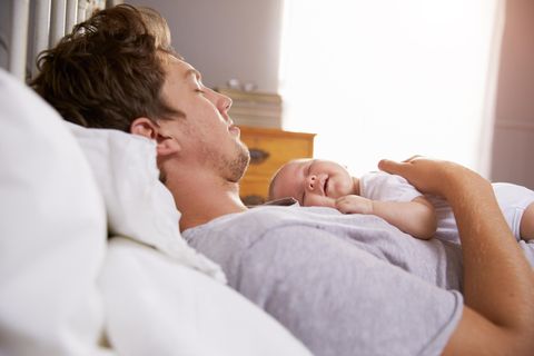 Eltern-Kind-Bindung: ein junger Vater liegt im Bett mit einem kleinen Baby auf der Brust