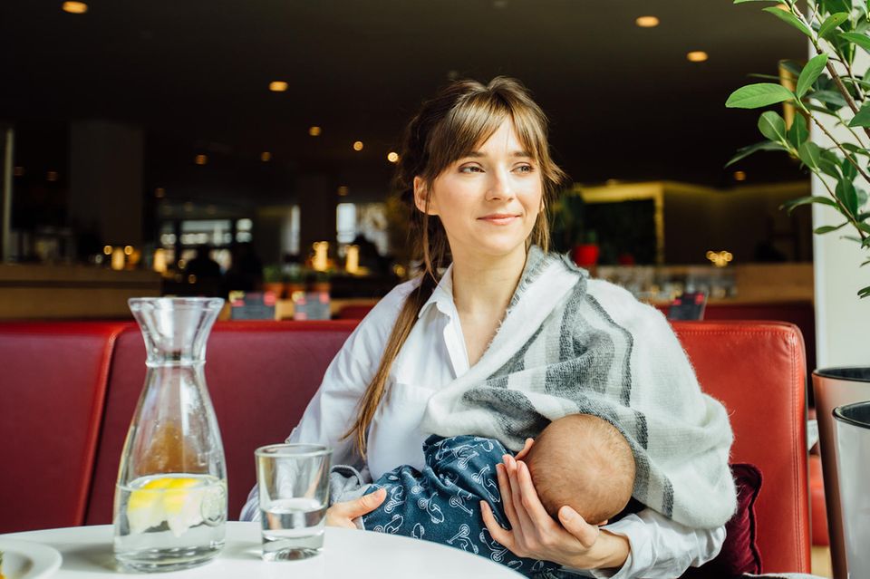 Entspannte Mutter stillt ihr Baby in einem Restaurant