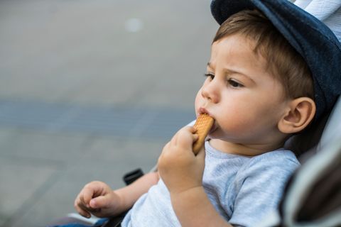 Kind sitzt im Buggy und isst einen Keks