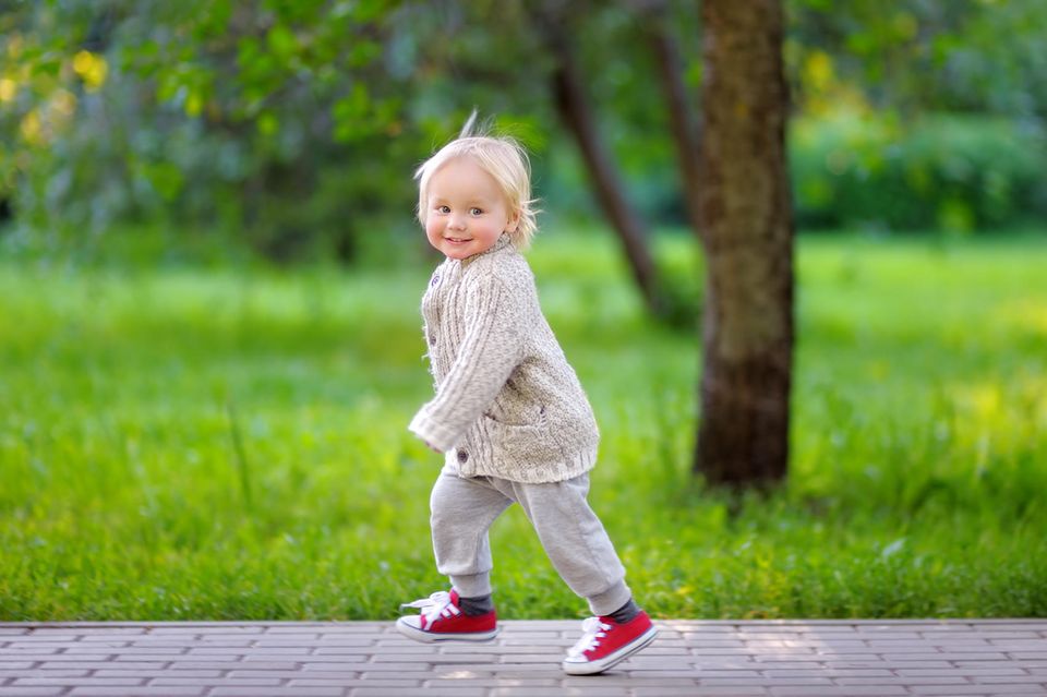 Kleines Mädchen rennt fröhlich durch den Park