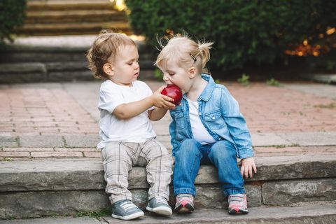 Kleinkinder teilen sich einen Apfel zum Essen