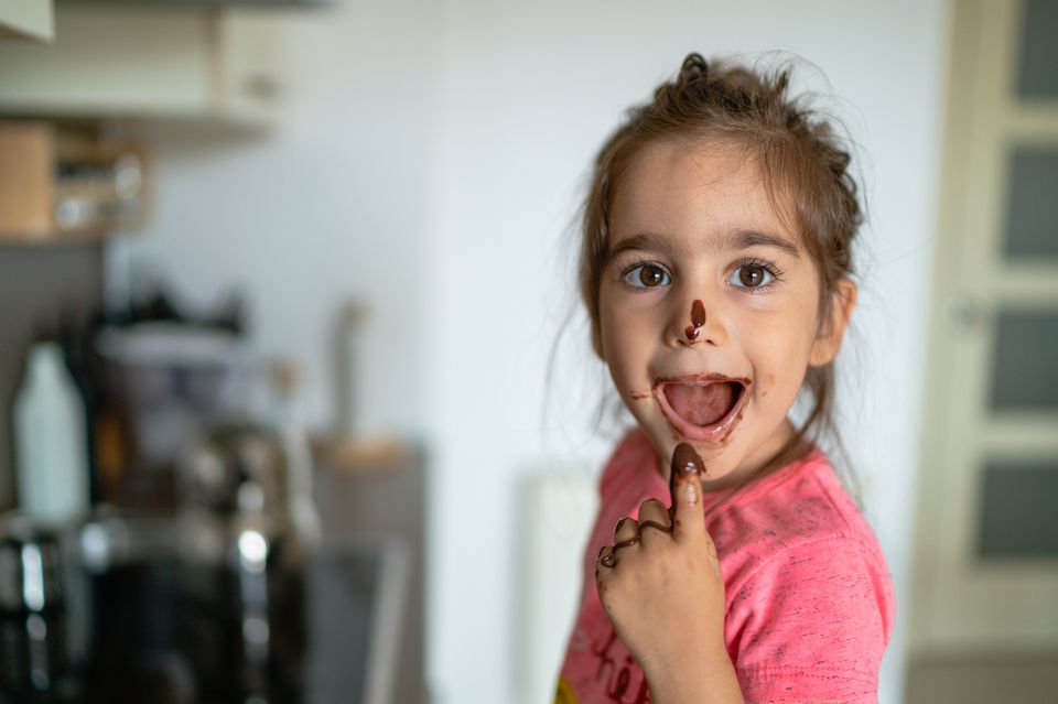 Mädchen isst Schokolade mit dem Finger