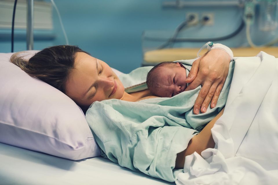 Mutter und Neugeborenes nach der Geburt im Krankenhausbett