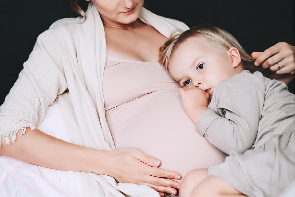 Schwangere mit Erstgeborenem auf dem Schoß