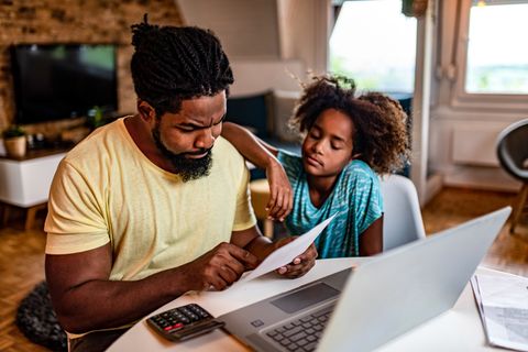 Vater und Tochter sitzen am Computer und rechnen