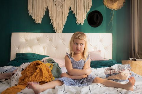 Verantwortungsbewusst: Kleines Mädchen faltet Kleidung und räumt das Zimmer auf